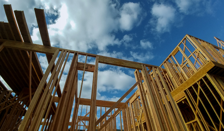 New residential construction house wood building frame against a blue sky.
