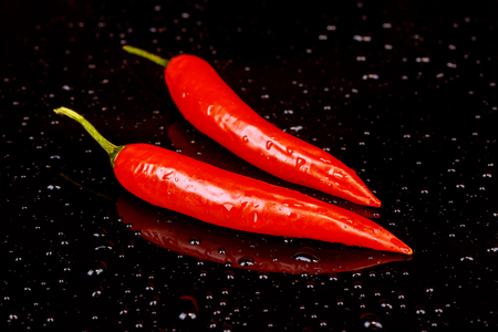 Red hot chili pepper on a dark background with space under the text bitter red pepper on a black backgroundの写真素材