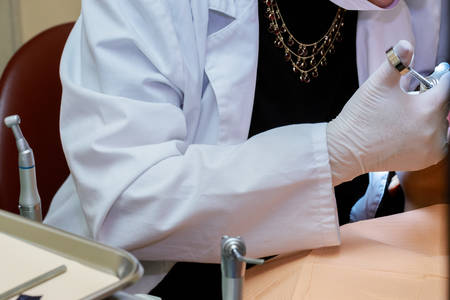 Dentists hands with tools in a patients mouth. Close up.