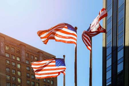 American flag against bright blue sky American flag against the sky and skyscrapersの写真素材