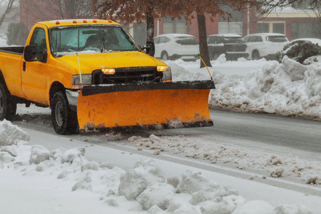 Snow plough truck clearing road after whiteout winter snowstorm blizzard for vehicle access snow...