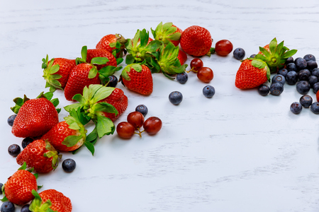 Flat lay, grapes, blueberries and strawberries on wooden table, copyspace blueberries grapes and strawberries on a white woodの写真素材