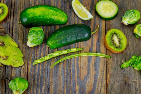 Fresh raw vegetable ingredients for healthy cooking or salad making with rustic olive wood board in center, top view, copy space. Diet or vegetarian foodの写真素材