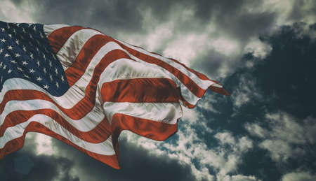 Majestic United States Flag against a blue sky with cloud closeup dark backgroundの写真素材