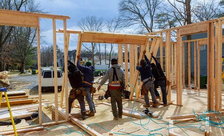 Construction Worker Using nail gun On wood building frame against House Buildの写真素材
