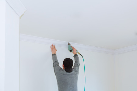 Man constructor renovates room interior with a wood crown molding in the ceilingの写真素材