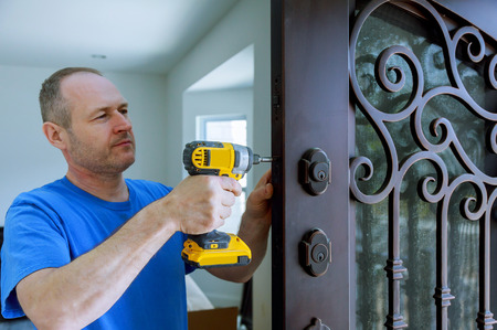 Installation of interior with a lock in the door leaf using an drill screwdriver,for holding screws, close-up.の写真素材