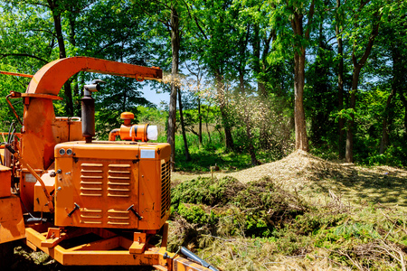 Wood Chipper in Action captures a wood chipper or mulcher shooting chips over a fence.の写真素材