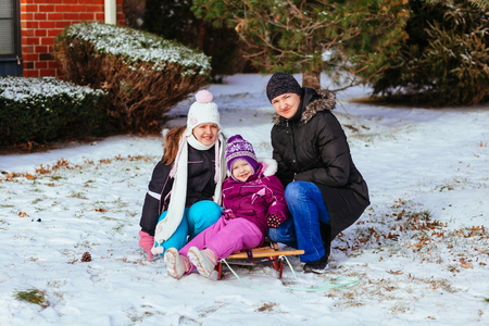 Young mother and her daughters having fun on winter day little girl playing in the street in winterの写真素材