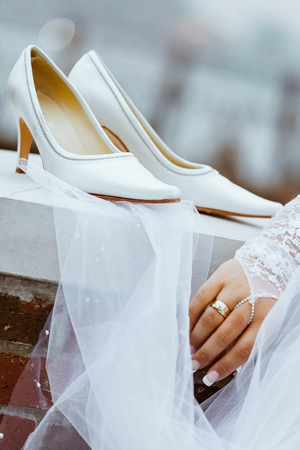 Wedding shoes with heels are hanging on a white fence before the bride wedding ceremony.の写真素材