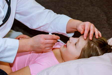 Doctor checking little girl's temperature medical exam, children and medicine conceptの写真素材