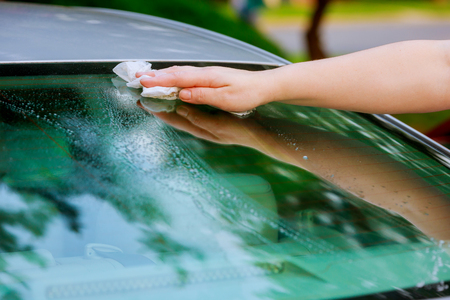 women hand dry wiping car surface with microfiber cloth after washing at parking lotの写真素材