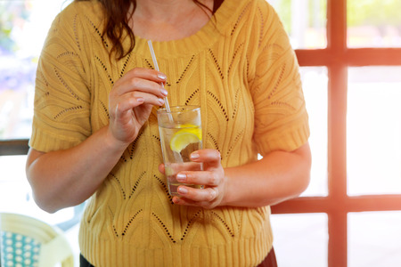 Womans hand holding a cold glass of soda and lemonの写真素材