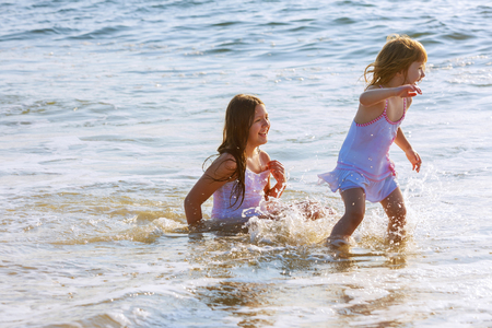 Little girl jumping and playing in the ocean in the big waves on beach.の写真素材