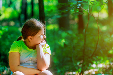 Beautiful little kid cute girl looking to one side in garden parkの写真素材