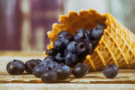 Freshly Juicy blueberries in the range of waffle cone. on rustic table. Concept of healthy eatingの写真素材