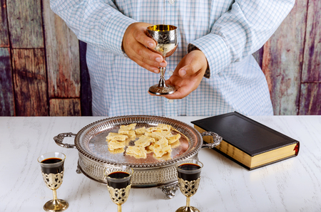 Holy communion cup of glass with red wine, bread and Holy Bible prayer for wine
