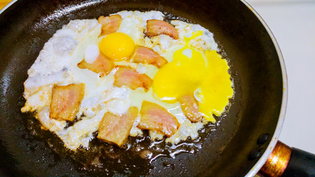 Scrambled fried eggs with bacon in a panの写真素材