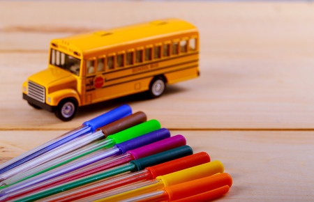 Back to school supplies colored pencils and toy yellow school bus on wooden backgroundの写真素材