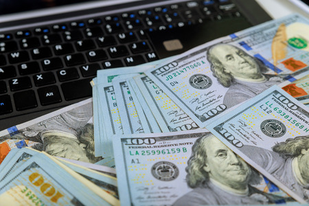 Credit cards and dollars on a laptop, close-up view.