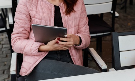 The girl is a teenager In her hands holds a tablet. He watches movie listening music on Internet social networks. The concept outdoor recreation.の写真素材