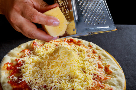 Preparation of dough for male hands rubbed cheese grated on pizza cookingの写真素材