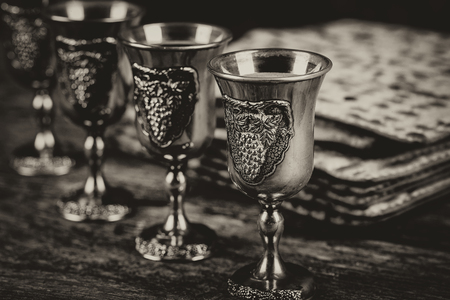 Red kosher four glasses wine with a of matzah a Passover Haggadah on a vintage wood backgroundの写真素材