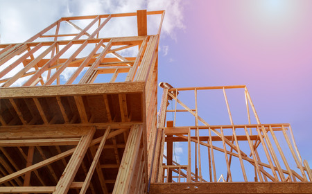 New residential construction house wood building frame against a blue sky.