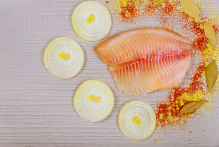 Raw tilapia fish fillet ready for cooking on cutting boardの写真素材