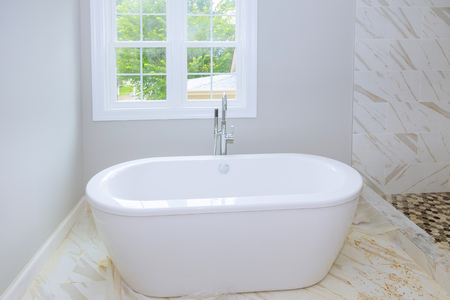 Bathroom interior with minimalistic design idea of new bathroom and shower. Tiled ceramic walls in bathroom, modern design with white tubの写真素材