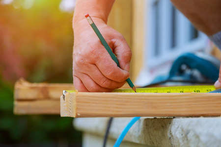 Carpenter using the writes a pencil on the wood beam a new home constructiion project