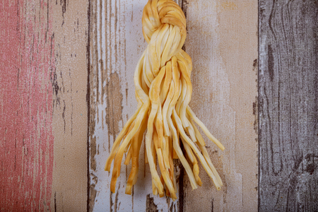 Delicious smoked braided wicker cheese on a wood background.