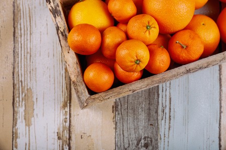 Fresh tangerines in old box with on wooden background. Top view