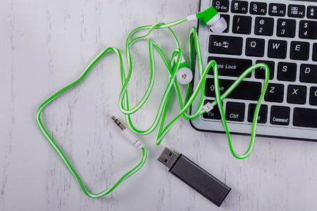 Keyboard notebook USB flash drive and earphone, equipment electronic on wood background