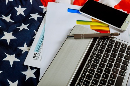 Words Tax Day , dollars and form 1040 income tax form showing tax day for April US flagの写真素材