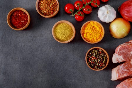 Raw pork meat steaks set of spices and herbs on black wood background. Top viewの写真素材