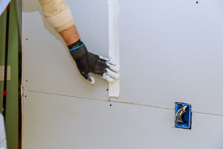 Man installing gypsum plasterboard construction with drywall installedの写真素材