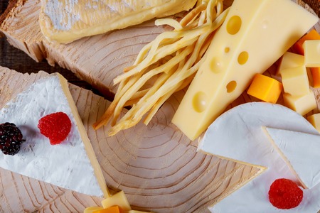 The assortment includes fruits and various types of cheese on wooden table.