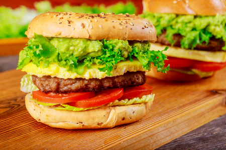 Juicy hamburger with lettuce and tomato fries homemade on cutting boardの写真素材