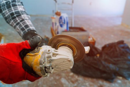 With electric grinder side working on paving tile on renovation bathroomの写真素材