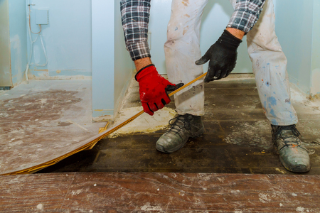 Handyman during work of removing oldlaminated parquet flooring home renovationの写真素材