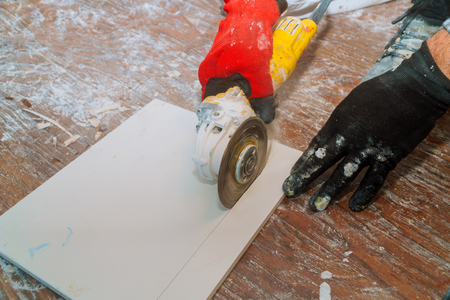 Man worker cutting beige tile with a circular saw on a cutting flooring tileの写真素材
