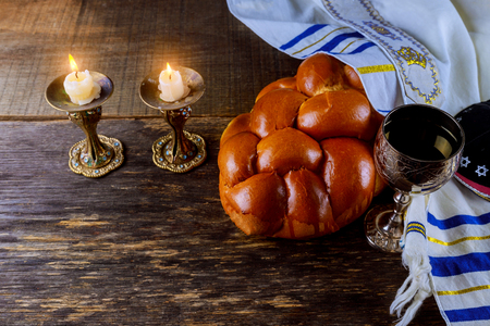 Shabbat eve table with covered challah bread, candles and cup of wine.の写真素材