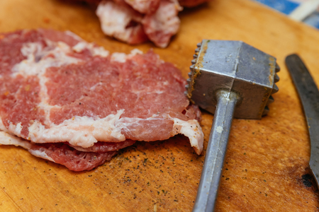 Hammer for meat and raw meat prepared for frying.