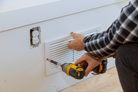 Man is installing the wall cover ventilation vent maintenance repair works renovation in the new home before installingの写真素材