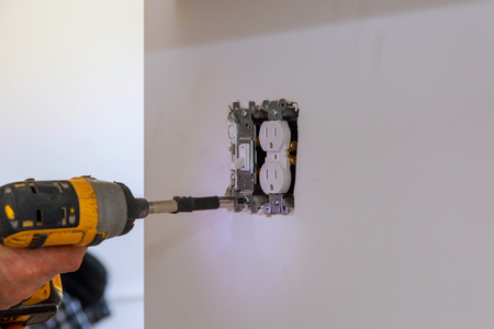 Electrician repairing wall switch indoors a newly kitchen wall.の写真素材