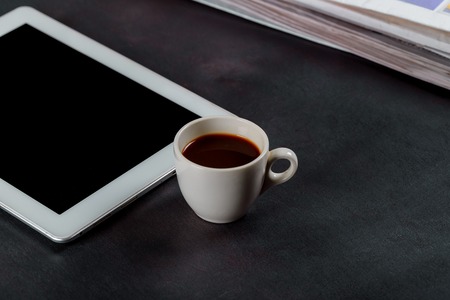 Tablet notepad and espresso coffee cup on office wooden tableの写真素材