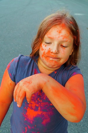 Closeup shot of young child covered with pinc color dry paint at Holi Festival.の写真素材