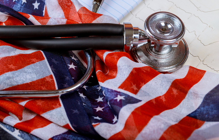 Stethoscope on American national flag and f ECG cardiogram pulse graph on a paperの写真素材