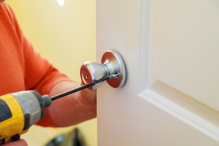 Handyman repair worker's hands installing new door locker man repairing the doorknob. closeupの写真素材